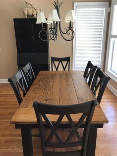 a dining room table with black chairs and a chandelier