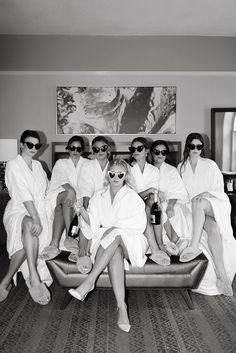 black and white photograph of six women in robes sitting on a couch wearing sun glasses