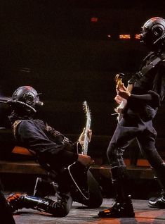 two people dressed as aliens playing guitars on stage