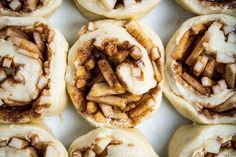 cinnamon rolls with icing are arranged on a white surface