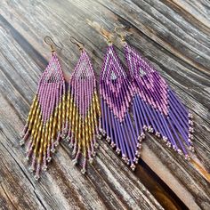 three pairs of purple and gold beaded earrings on wooden table with wood planks