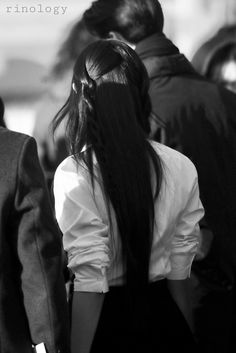 black and white photograph of woman with long hair walking down the street in front of other people