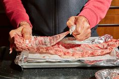 a person cutting up meat on top of tin foil