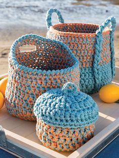 three crocheted baskets on a tray with lemons and water in the background