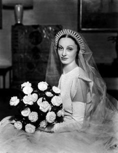 an old black and white photo of a woman in a wedding dress holding a bouquet of flowers