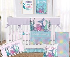 a baby crib bedding set with mermaid themed sheets, pillows and pictures on the wall