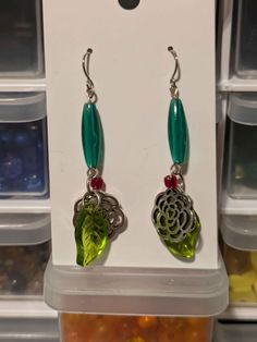 These earrings have stainless steel earring hooks. The long green plastic tube beads are vintage from the '90s, the green leaf charms are glass, and the flower charms are silver-tone. For reference, this mannequin's head is a bit smaller than an average adult head. Green Drop Flower Earrings, Green Flower Drop Earrings, Green Flower-shaped Pierced Earrings, Nickel Free Green Metal Earrings, Nickel-free Green Metal Earrings, Green Beaded Pierced Earrings, Green Adjustable Dangle Flower Earrings, Green Nickel Free Dangle Earrings, Nickel-free Green Dangle Earrings