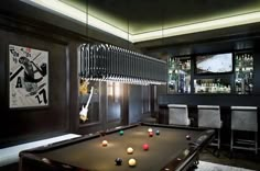 a pool table in the middle of a room with bar stools and pictures on the wall