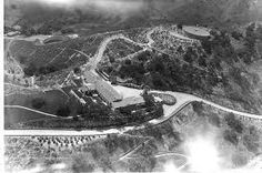 an aerial view of a large building on top of a hill with clouds in the sky