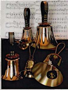 an assortment of antique brass bells on sheet music