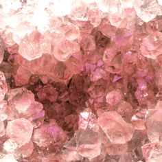 pink crystals are scattered on top of each other in this close up photo, with the light shining through them