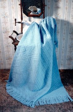 a blue blanket sitting on top of a wooden chair next to a wall mounted mirror