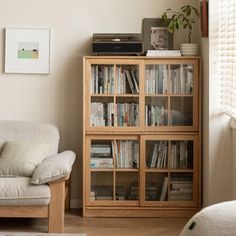 a living room with a couch, book shelf and television on top of the cabinet