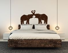 two elephants are standing next to each other on a bed with white sheets and pillows