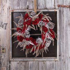 a wreath with pine cones is hanging on a wooden door, decorated with burlap