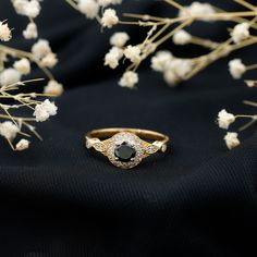 two wedding rings sitting next to each other on a black cloth with flowers in the background