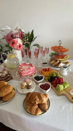 a table topped with lots of different types of cakes and pastries next to wine glasses