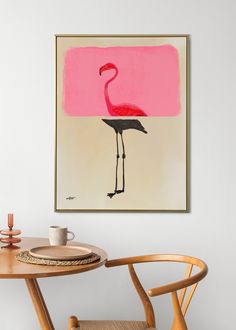 a pink flamingo painting hanging on the wall next to a wooden table and chairs