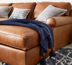 a brown leather couch sitting on top of a blue rug