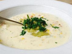 a white bowl filled with soup and garnished with parsley on the side