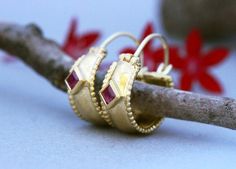 Wide ornamented solid yellow, white or rose gold hoop earrings with rubies in 14k, 18, or 22k gold. These Gold Hoop earrings are a special take on ornamental jewelry.These wide oriental-style hoops feature beaded edges and are set with beautiful square shiny red rubies.Rubies, the birthstone of July, are considered the king of gems and represent love, health, and wisdom. It was believed wearing a fine red Ruby bestowed good fortune on its owner. It is a favorite gem among those in power and thos Elegant Small Hoop Earrings With Bezel Setting, Fine Jewelry Bezel Set Hoop Earrings As Gift, Anniversary Hoop Earrings With Bezel Setting, Gold Hoop Earrings With Bezel Setting, Yellow Gold Huggie Earrings With Bezel Setting As Gift, Yellow Gold Huggie Earrings Gift, Bezel Set Hoop Huggie Earrings As Gift, Hoop Huggie Earrings With Bezel Setting As Gift, Gift Huggie Hoop Earrings With Bezel Setting