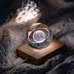 a clear glass ball sitting on top of a wooden block in the middle of a bed