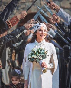 a woman in a white dress is holding flowers and some people are standing behind her