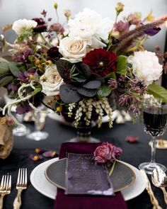 the table is set with purple and white flowers, silverware, and napkins