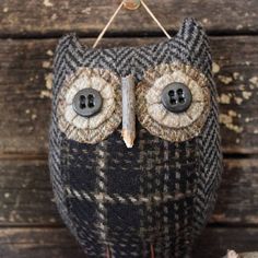 an owl made out of fabric with buttons on it's eyes is hanging from a string