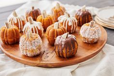 a wooden plate topped with mini pumpkins covered in frosting