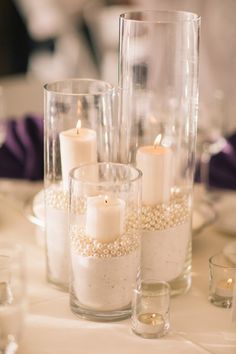 some candles are sitting in glass vases on a table