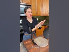 a woman standing in front of a pan on top of a wooden counter