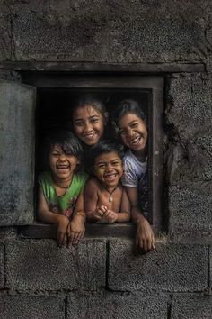 four children are smiling and looking out the window