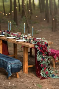 a wooden table topped with flowers and candles next to a bench covered in red velvet