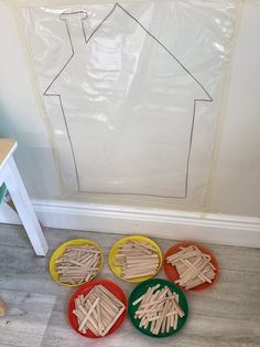 four plates with popsicle sticks in front of a house cutout