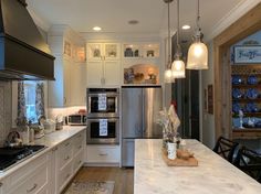 a kitchen with white cabinets and stainless steel appliances, along with an island countertop