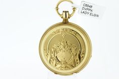 This Lady Elgin pocket watch is made in 18K yellow gold and is a key-wind and set. It has a hand engraved floral pattern ob both the front and back with ribbon going around the initials "S.C.A" and a mountain side scene. The watch has a sunken dial the case is marked 91216, the movement is signed Lady Elgin, it has a blank dust cover, and the movement is marked 225340. The case measures 43.92mm round and sits 12.40mm tall.This watch is in working condition and comes with a 1 year guarantee.--Ple Elegant Yellow Gold Pocket Watch, Victorian Yellow Gold Pocket Watch With Chronometer, Victorian Yellow Gold Pocket Watch For Anniversary, Luxury Pocket Watch Chronometer For Anniversary, Elegant Yellow Gold Medallion Pocket Watch, Elegant Yellow Gold Circular Pocket Watch, Victorian Yellow Gold Watch For Gift, Luxury Yellow Gold Pocket Watch With Chronometer, Elegant Hallmarked Pocket Watch For Collectors