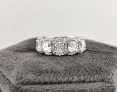 three stone diamond ring on top of a gray furnishe cushioned surface in front of a white background