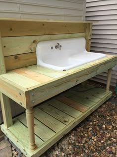 a sink sitting on top of a wooden shelf next to a building with siding around it