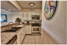 a kitchen with marble counter tops and white cabinets, along with a stainless steel stove top oven