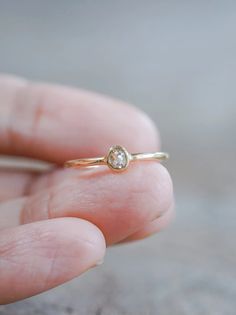 a person's hand holding a gold ring with a white diamond on the side