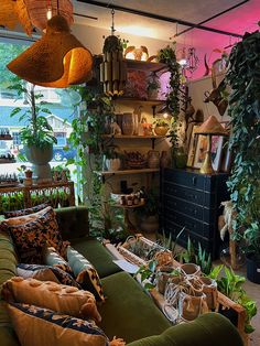 a living room filled with lots of green furniture and potted plants on top of shelves