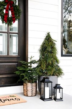 a christmas tree and two lanterns on the front porch