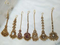 five pairs of earrings are displayed on a white cloth covered tablecloth in this image