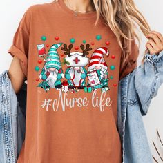 a woman wearing an orange nurse shirt with reindeers and christmas hats on her head