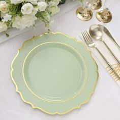 a table setting with flowers and silverware on it, including a green dinner plate