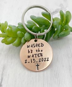 a metal keychain with the words washed by the water on it