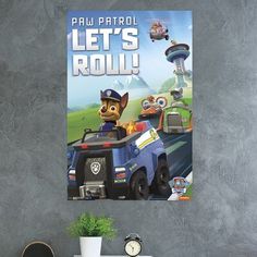 paw patrol let's roll poster hanging on the wall in a room with a desk and chair