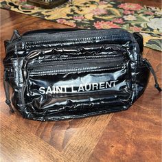 Crossbody Bag With Two Zipped Pouches And Three Flat Zipped Pockets With Shoelace Pulls, Decorated With A Saint Laurent Paris Embossed Leather Label On The Front. Chic Black Bag With Silver-tone Logo Plaque, Saint Laurent Lou Crossbody Bag, Crossbody Bag Saint Laurent, Saint Laurent Men Bag, Saint Laurent Pouch, Saint Laurent Paris, Leather Label, Saint Laurent Bag, Cross Body Bag