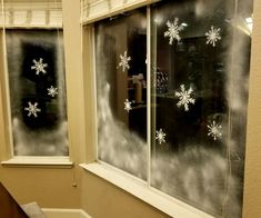 two windows with snowflakes on them in a room next to a window sill